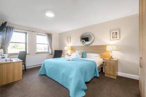 a hotel room with a bed with a blue blanket at Tollyrose Country House in Newcastle