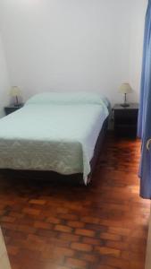 a bedroom with a bed and two tables with lamps at Departamento frente a Plaza España in Mendoza