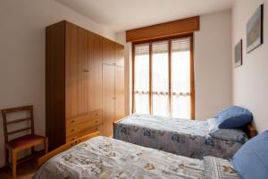 1 dormitorio con 2 camas, silla y ventana en Appartamento vista Alpi biellesi, en Biella