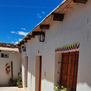 a white building with a wooden door and a blue sky at Hostería el Sol Naciente in Tilcara