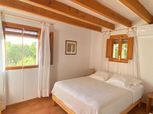 a bedroom with a white bed and a window at Ses Oliveres in Cala Saona
