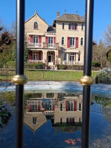 uma casa é refletida em uma piscina de água em Le Pavillon de St Agnan em Hautefort