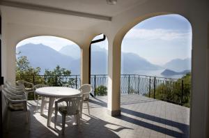 uma varanda com mesa, cadeiras e montanhas em Como Lake Samlu House - Menaggio em Plesio
