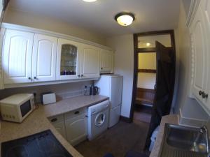 a kitchen with white cabinets and a white refrigerator at Beldy Chapel Ground floor apartment in Alston