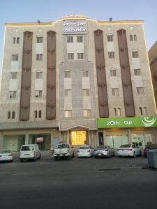 a large building with cars parked in a parking lot at VIP For Apartment - شقق فاخره in Al ‘Awālī