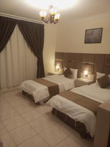 a hotel room with two beds and a chandelier at VIP For Apartment - شقق فاخره in Al ‘Awālī