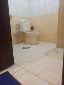 a bathroom with a toilet and a tiled floor at VIP For Apartment - شقق فاخره in Al ‘Awālī