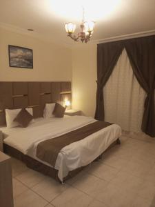 a bedroom with a large bed and a chandelier at VIP For Apartment - شقق فاخره in Al ‘Awālī