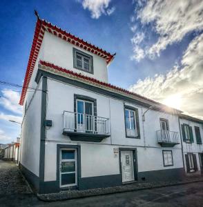 een wit huis met 2 balkons in een straat bij Matriz Guest House in Ribeira Grande