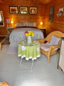 Un dormitorio con una cama y una mesa con flores. en The Log Cabin, en Wimborne Minster