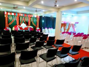 a banquet hall with black chairs and a stage at The Royal Chandra in Samastīpur
