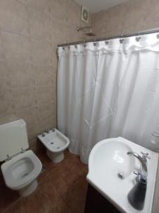 a bathroom with a toilet and a white shower curtain at Depto Caba Floresta in Buenos Aires