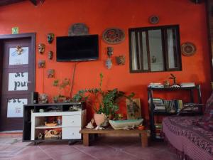 ein Wohnzimmer mit einer orangefarbenen Wand und einem TV in der Unterkunft Floripa Beach House Hostel in Florianópolis