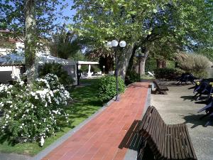 um parque com bancos, flores brancas e árvores em Hotel Eden Sul Lago em Bolsena