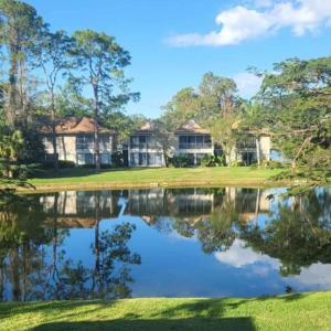 une maison sur un parcours de golf avec une réflexion dans l'eau dans l'établissement Stunning Lake View-Emilio Sanchez Tennis Academy, à Naples