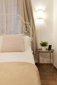 un lit avec une tête de lit blanche et une table avec une lampe dans l'établissement Bijou home suite - Vaticano, à Rome