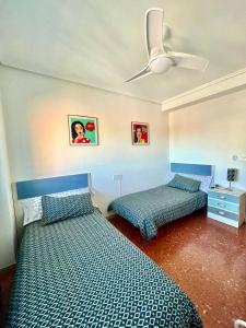 a bedroom with two beds and a ceiling fan at Apartamento La Zahora - Alcañiz in Alcañiz