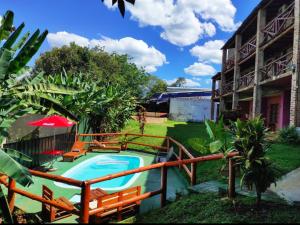 una piscina con sillas y una sombrilla junto a un edificio en Hotel Village del Sol en Puerto Iguazú