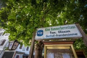 un cartello per un negozio di fronte a un albero di Gasthof Altes Hammerherrenhaus a Übelbach