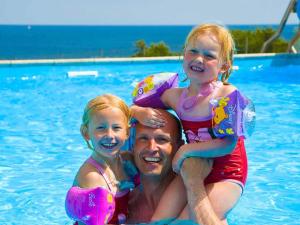 un hombre y dos chicas en una piscina en 5 person holiday home on a holiday park in Gudhjem, en Gudhjem