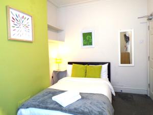 een slaapkamer met een bed met lemen groene muren bij Lynam House in Stoke on Trent