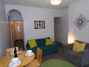 een woonkamer met een blauwe bank en een tafel bij Lynam House in Stoke on Trent