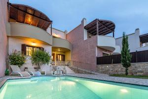 a house with a swimming pool in front of a house at Pearls Of Crete - Holiday Residences in Makry Gialos