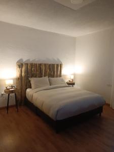 a bedroom with a large bed with a wooden headboard at Hacienda El Castillo Hotel Boutique in Pasto