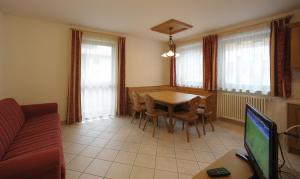 a living room with a table and chairs and a television at Appartamenti Villa Elisa in Falcade