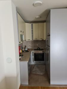 a kitchen with white cabinets and a sink and a refrigerator at Apartman Jaca in Tuzla