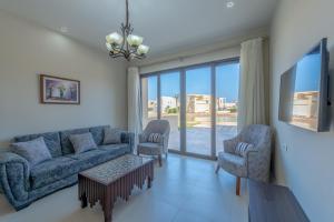 a living room with a couch and two chairs and a tv at Brand-New Family House in Tawila El Gouna Lagoon and Pool Access in Hurghada