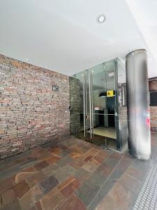 un vestíbulo con un ascensor de cristal en una pared de ladrillo en Departamento Monoambiente Puerto Madero y Retiro en Buenos Aires