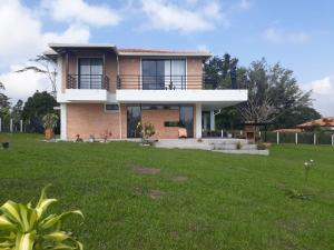 une maison avec une pelouse verte devant elle dans l'établissement Casa Campestre Altamira, à Los Curos