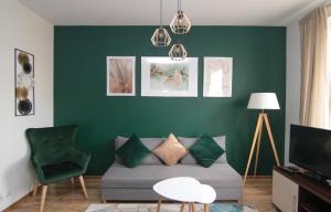a living room with a couch and a green wall at DMK Green Apartment near Warsaw-Modlin Airport in Nowy Dwór Mazowiecki
