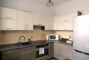 a kitchen with white cabinets and a sink and a refrigerator at DMK Green Apartment near Warsaw-Modlin Airport in Nowy Dwór Mazowiecki