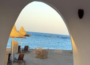 uma praia com cadeiras e guarda-sóis e o oceano em Dolphin Continental Hotel em El Quseir