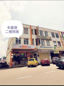 a yellow car parked in a parking lot in front of a building at MersingFirstFloor丰盛港二楼民宿 in Mersing