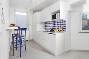 a kitchen with white cabinets and blue bar stools at AMORE RENTALS - Appartamento Luis 2 11 in Sorrento