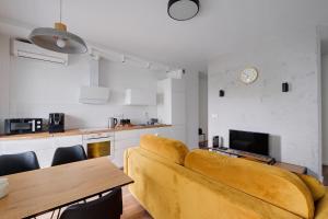 a living room with a yellow couch and a kitchen at Targowa 10 Modern 2BR Apt in Warsaw
