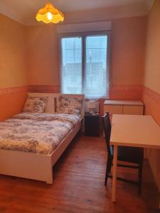 a bedroom with a bed and a table and a window at Maison le Diamant vert in Bezons