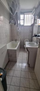 a bathroom with a tub and a toilet and a sink at Maison le Diamant vert in Bezons