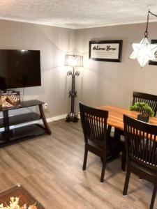 a living room with a wooden table and a television at The House Hotels - 4 Beds, huge yard, secluded, and central! in Akron