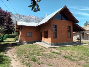 a small brick house with mountains in the background at Casa Peral in El Bolsón