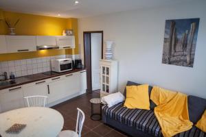 a kitchen and a living room with a couch and a table at Gite Bergues Centre in Bergues