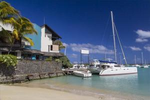 a boat is docked at a marina with a house at Résidence Bleu Azur in Grand Baie