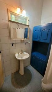 baño con lavabo, espejo y puerta azul en La Baguala del Candil, Casa Rural, Pileta y Parque en Solís