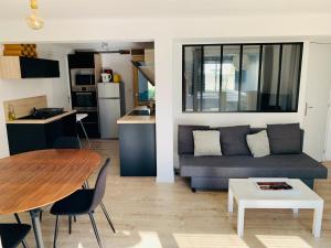 ein Wohnzimmer und eine Küche mit einem Sofa und einem Tisch in der Unterkunft Appartement rez de jardin bord de mer (Sweet Home) in Saint-Malo