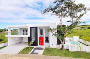 a white house with a red door and a tree at Luxury Tropical Paradise Villa 4B Heated Pool in Camú