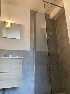 La salle de bains est pourvue d'une douche avec une porte en verre. dans l'établissement au 33 chambres d'hôtes, à Saint-Omer