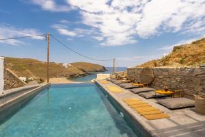 una piscina con sedie e vista sull'oceano di The Mykonist Merchia Beach Villas & Suites a Merchia Beach